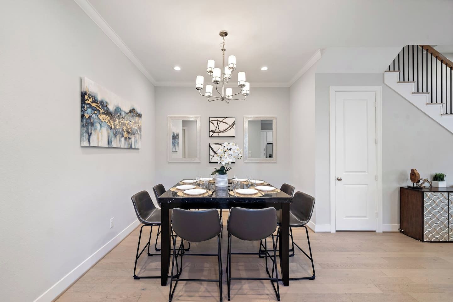 A dining area with a black table, six chairs, and a chandelier.