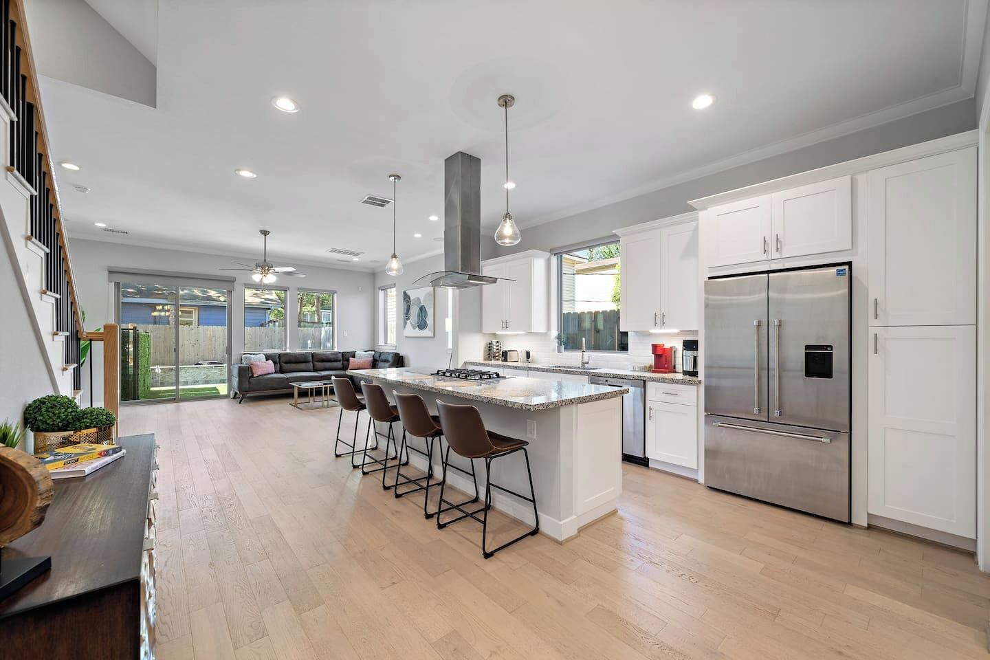 A modern kitchen with a central island, stainless steel appliances, and a dining area with bar stools.