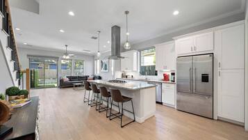 A modern kitchen with a central island, stainless steel appliances, and a dining area with bar stools.