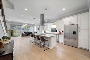 A modern kitchen with a central island, stainless steel appliances, and a dining area with bar stools.