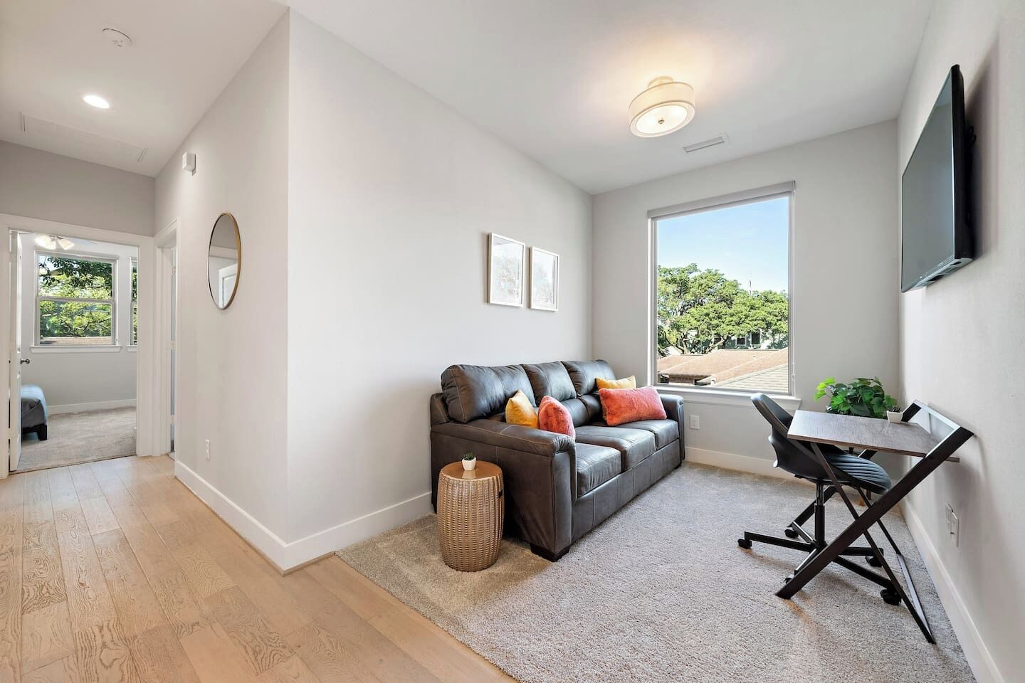 A modern living room with a leather sofa, a small table, and a view through a large window.
