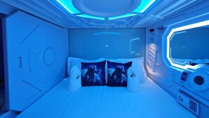 Une pièce futuriste avec un lit, un panneau de contrôle et une grande fenêtre.