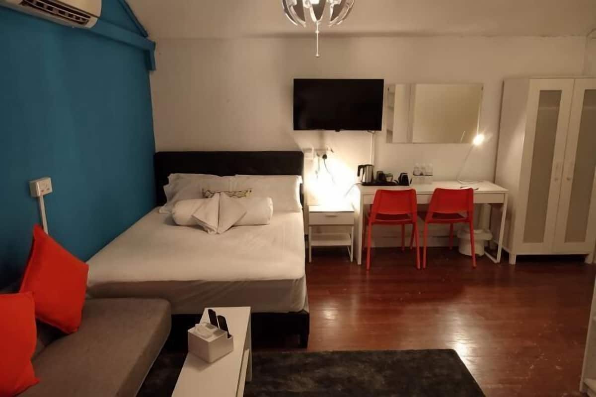 Una habitació d'hotel amb un llit, una taula de treball, una cadira, una televisió i un armari.