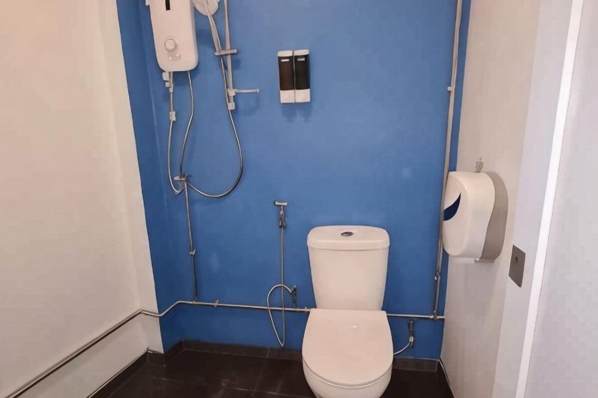 Un baño pequeño con inodoro, secador de manos y dispensador de toallas de papel.