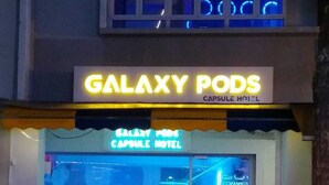 L’extérieur de l’hôtel-capsule Galaxy Pods, avec son enseigne au néon, son espace détente et son design moderne.