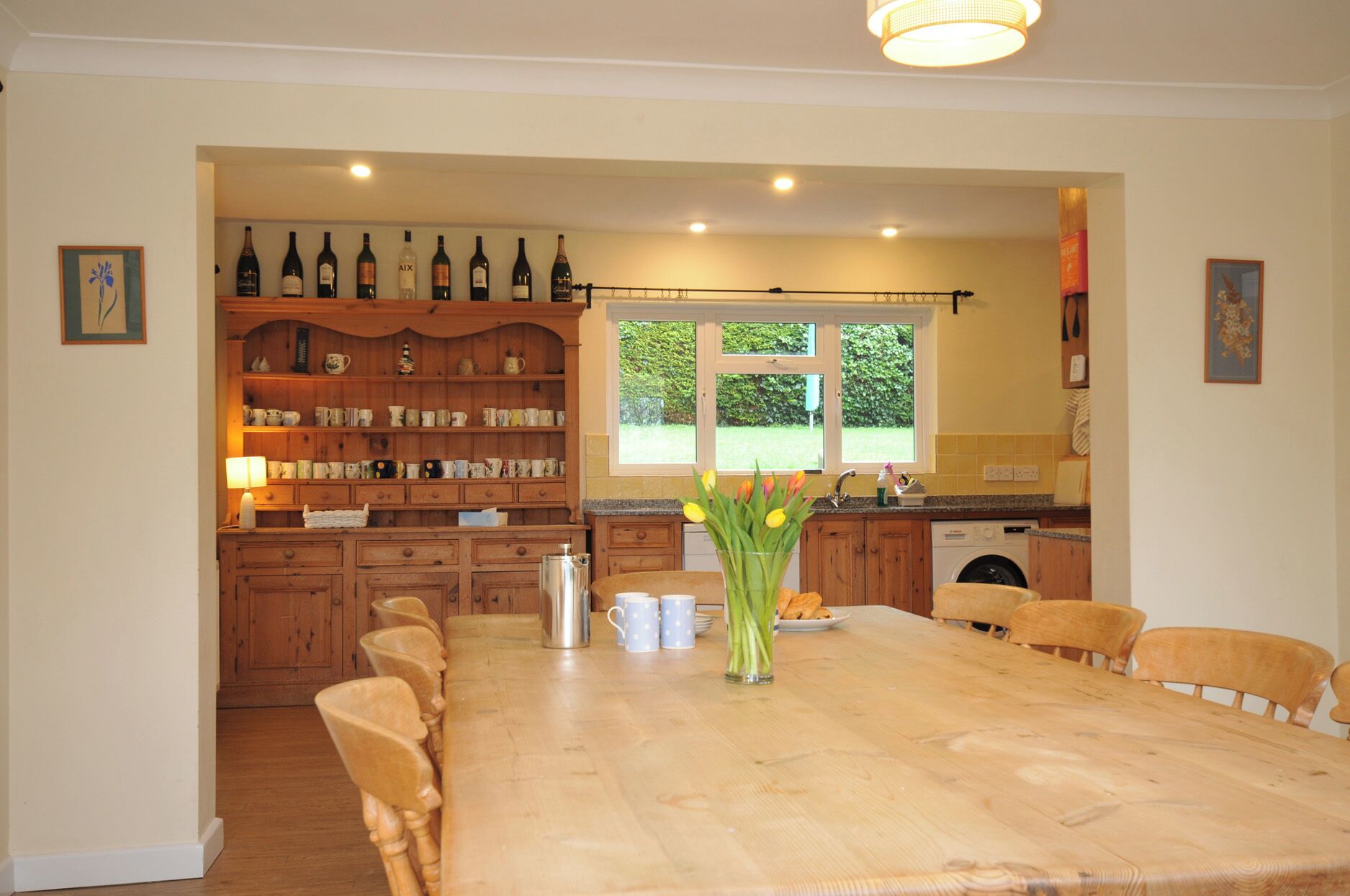 Una cocina amplia con armarios de madera, una mesa de comedor y un ventanal con vista a la vegetación.