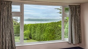 Una habitación con un ventanal grande que da a un paisaje verde y una masa de agua.