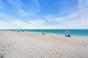 A beach with a clear sky, a few umbrellas, and a few people. - Island Breeze Condo's (Englewood)