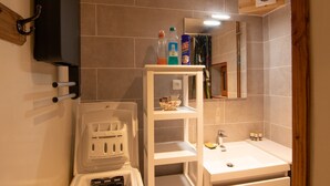 A bathroom with a toilet, a sink, and a shelf with toiletries. - Gîte in Donezan (Quérigut)