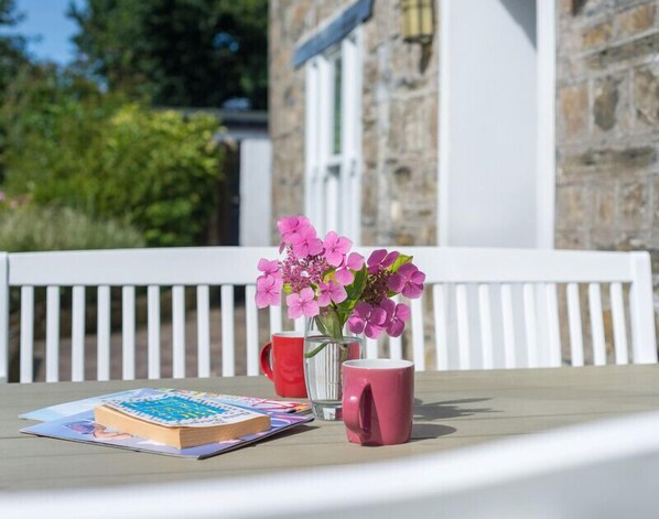 A table with a cake, a pink mug, and a vase with pink flowers.