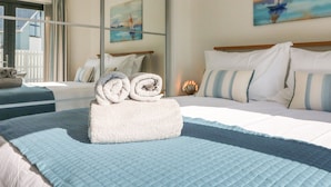 A hotel room with a bed, a window with curtains, a painting on the wall, and a lamp on the nightstand. - Seaquel (Bideford)