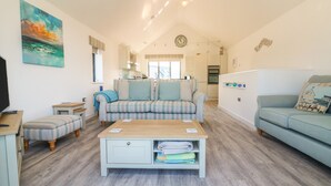 A modern living room with a sofa, a coffee table, and a TV. - Seaquel (Bideford)