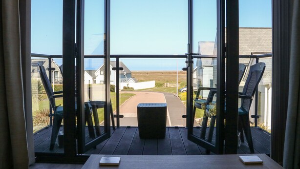 A balcony with a view of a residential area, a table, and two chairs. - Seaquel (Bideford)