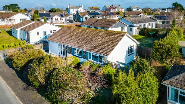 A residential area with multiple houses, some with solar panels, surrounded by greenery and a clear sky. - Little Sailing (Wadebridge)