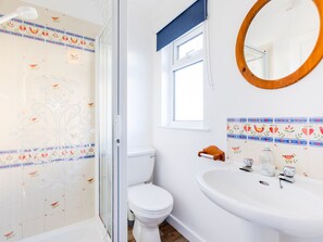 A bathroom with a shower, toilet, sink, and a mirror. - Little Sailing (Wadebridge)