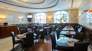 A spacious restaurant with high ceilings, chandeliers, and large windows. - York International Hotel (Dubai)