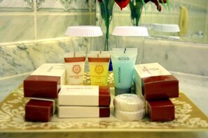 A variety of toiletries including shower caps, a bottle of shampoo, and a bottle of bath foam on a tray.