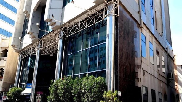 A modern building with a glass facade, multiple floors, and a prominent entrance with a metal framework. - York International Hotel (Dubai)