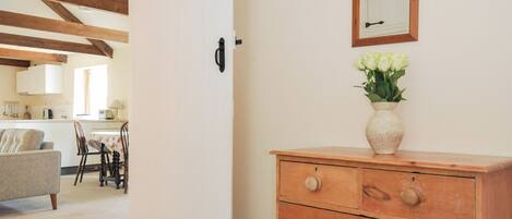 Una habitación con un aparador de madera, un espejo y un jarrón con flores.