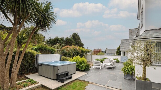 A patio with a hot tub, outdoor seating, and a garden with palm trees. - Cherrytrees (Wadebridge)