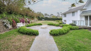 A stone pathway leading to a white house with a garden. - Cherrytrees (Wadebridge)
