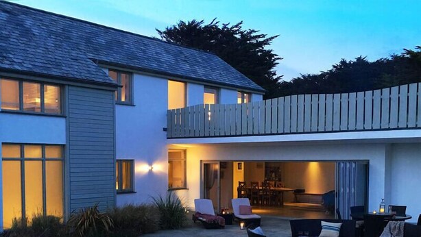 A modern house with a patio area featuring outdoor seating and a fire pit. - Downalong (Wadebridge)