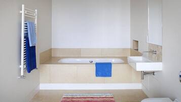 A modern bathroom with a bathtub, a sink, and a toilet.
