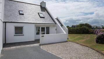 A modern house with a sloped roof, a small porch, and a gravel driveway.