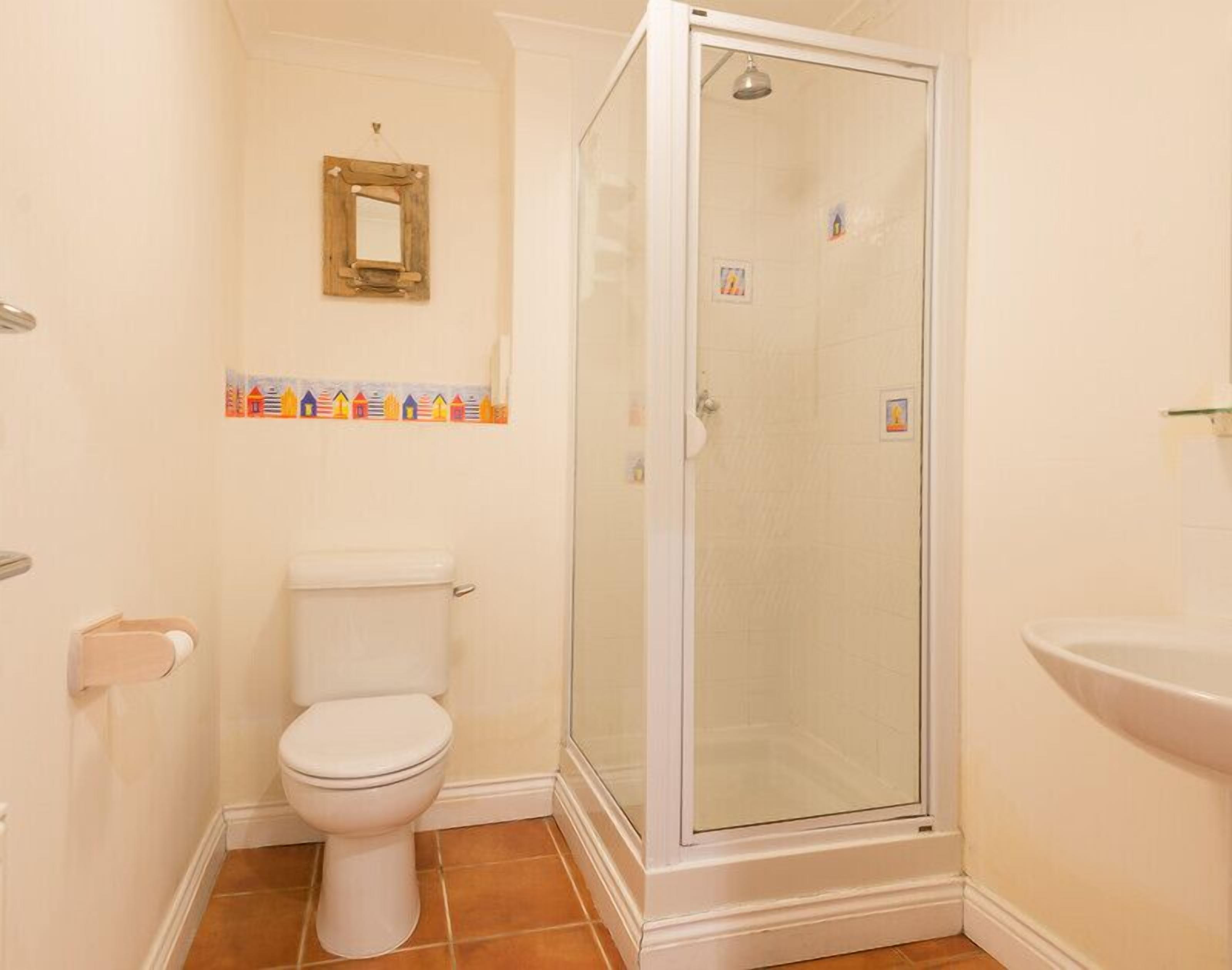 A bathroom with a toilet, a glass shower enclosure, and a sink.