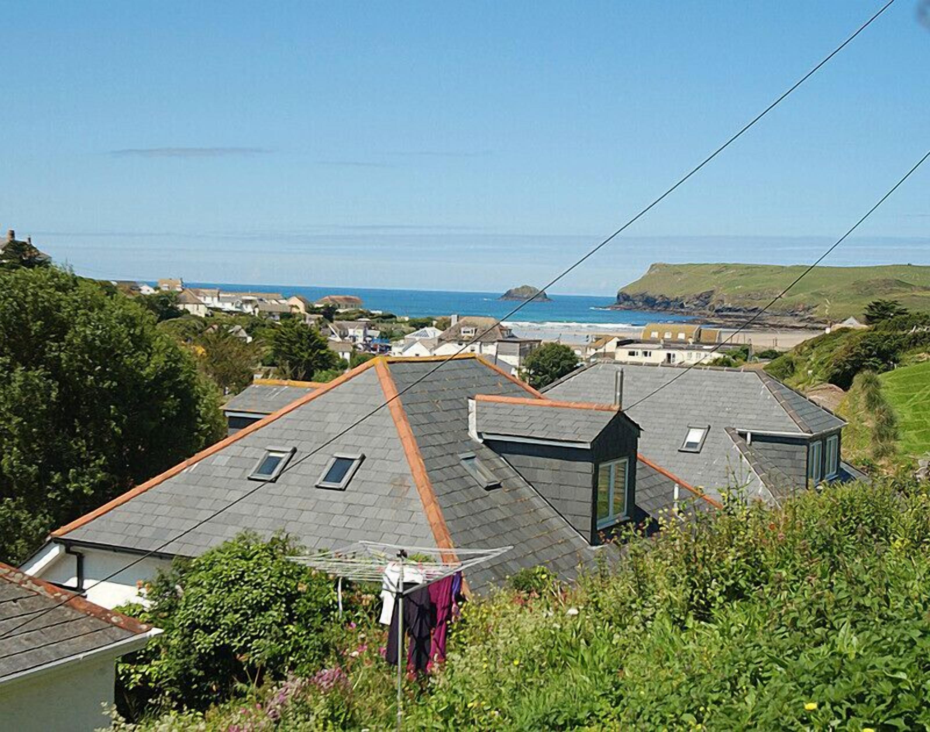 A residential area with houses, a view of the sea, and a hillside.