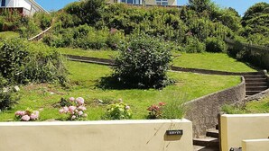 A residential area with a house on a hill, a paved path, and a sign reading "BURWYN".