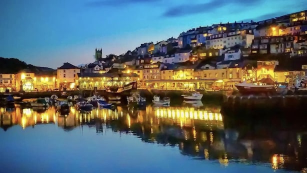 A waterfront town at dusk with buildings reflecting on calm water, boats docked, and a hill in the background. - Lovely Apartment Sleeps 6 Singles in Torquay (Torquay)
