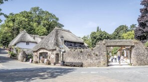 A traditional stone building with a thatched roof, a bench, and a signpost. - Lovely Apartment Sleeps 6 Singles in Torquay (Torquay)