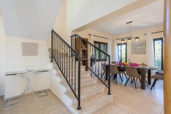 A modern interior with a staircase, dining area, and kitchen.