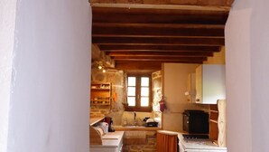 Une cuisine rustique avec des murs en pierre, des poutres en bois et une petite fenêtre.