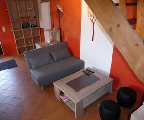 Un salon avec un canapé gris, une table basse en bois et une petite table d’appoint.