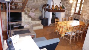 Un coin repas rustique avec un mur en pierre, des meubles en bois et une cheminée.