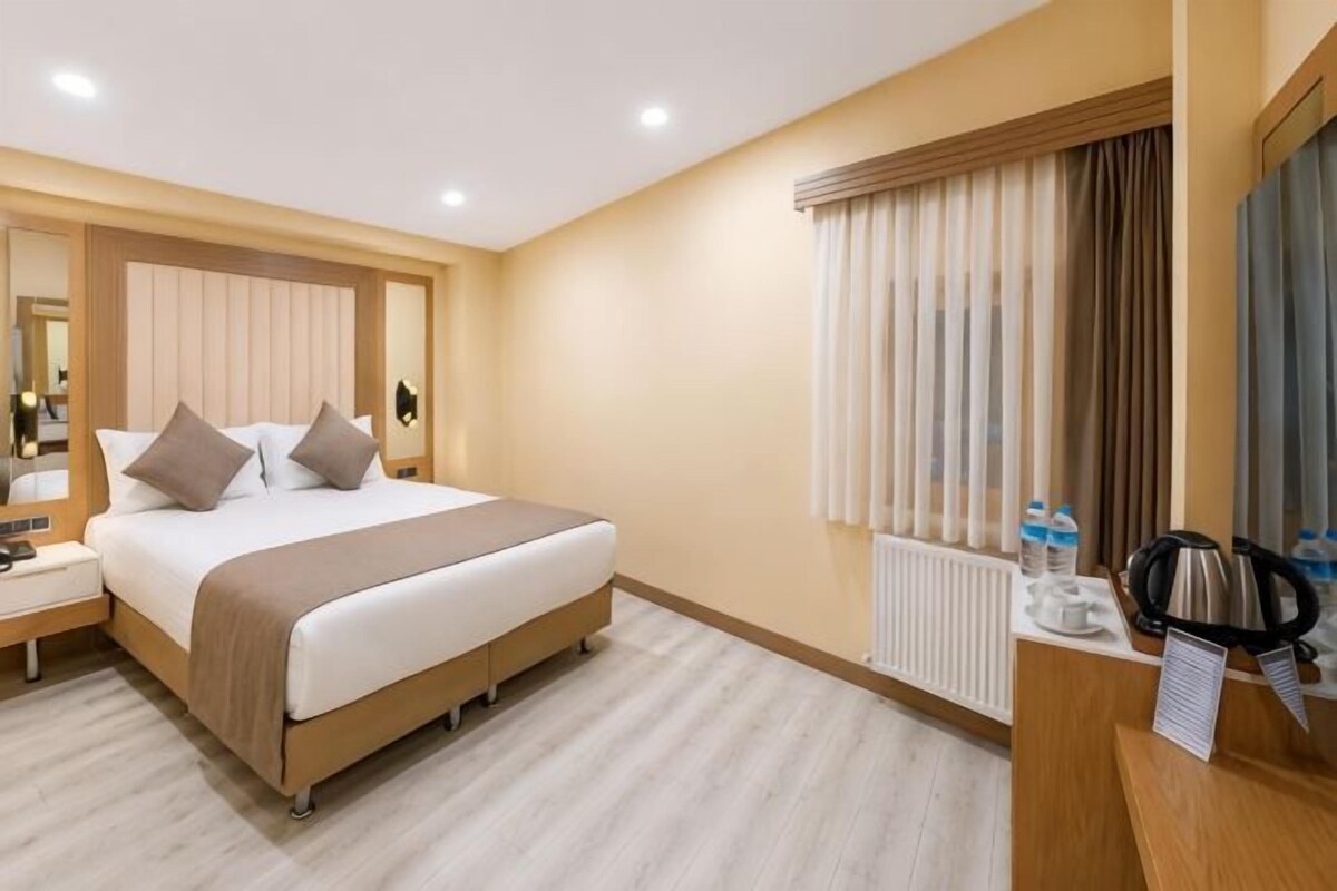 Een hotelkamer met een bed, nachtkastje en spiegel.