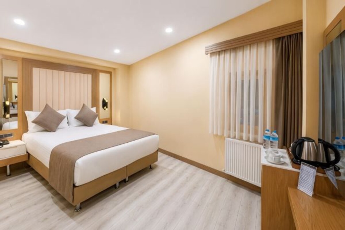Una habitación de hotel con cama, mesita de noche y espejo.