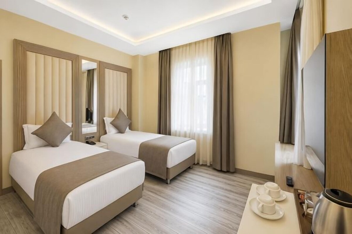 Een hotelkamer met twee bedden, een bureau, een spiegel en een televisie.