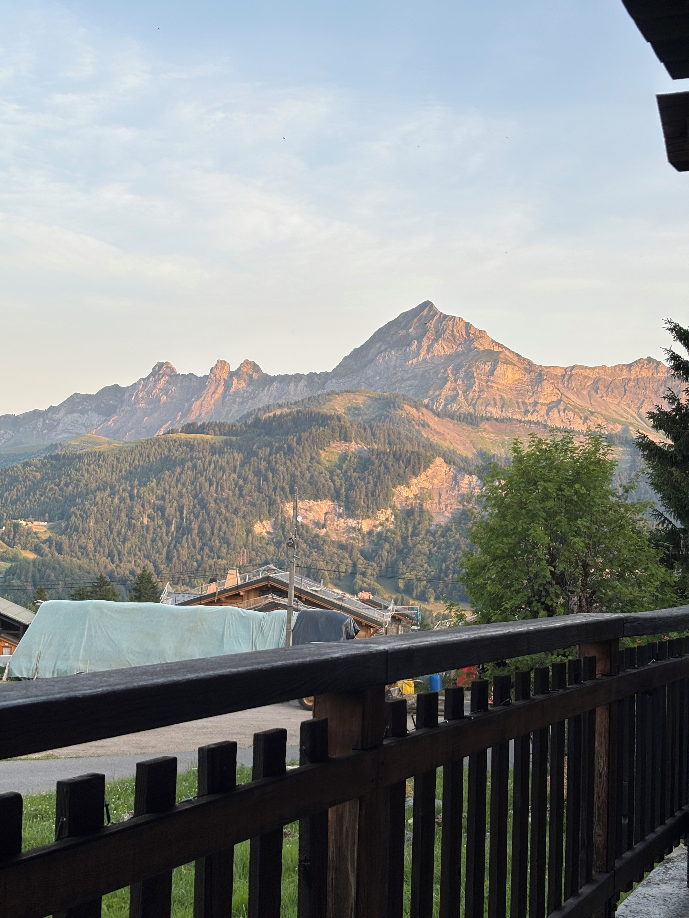 Une vue sur la montagne depuis un balcon en bois doté d’une rambarde en métal.