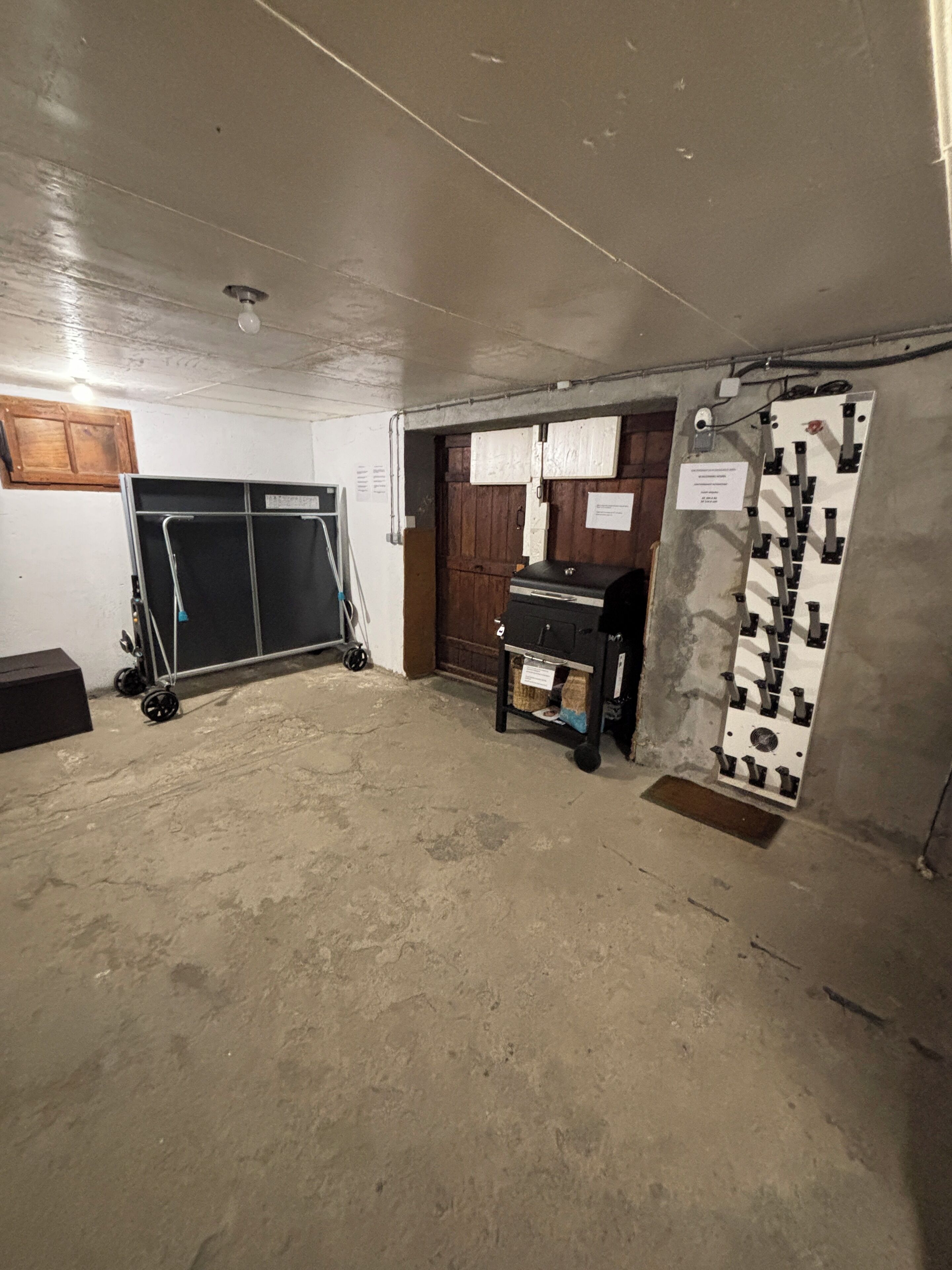 A room with a concrete floor, a wooden door, a metal cabinet, and a ceiling fan.