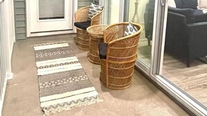 Un patio cubierto con sillas de mimbre, un ventanal y vistas al interior.