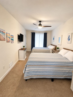A bedroom with two beds, a ceiling fan, a TV, and artwork on the walls. - Majestic Waterfront Condo on Rehoboth Bay Minutes From The Beach, Sleeps 8-10 (Lewes)
