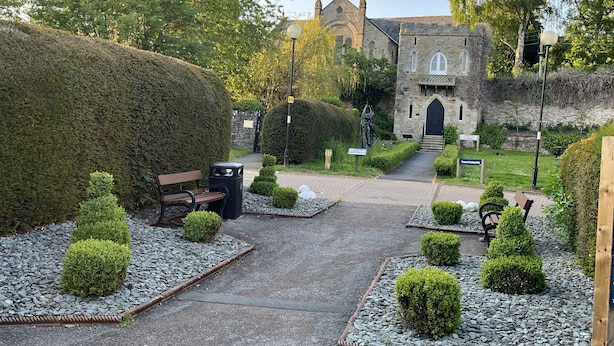 A stone building with a large entrance, surrounded by neatly trimmed hedges and a gravel pathway leading to it. - Bracken Cottage (Bishop Auckland)
