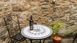 A table with a bottle of Castelmargo Merlot, two glasses, and a potted plant. - Bracken Cottage (Bishop Auckland)