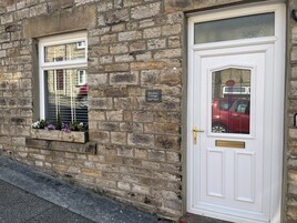Un edificio de piedra con una puerta blanca y una ventana con un letrero que dice "Bracken Cottage".