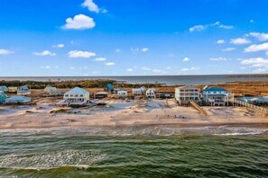A coastal area with multiple beach houses, some with attached docks, and a view of the ocean.