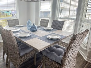 A dining area with a wooden table set for six, surrounded by wicker chairs with grey cushions. - Stunning Beach Views, Dogs Welcome/Family Friendly! (Gulf Shores)