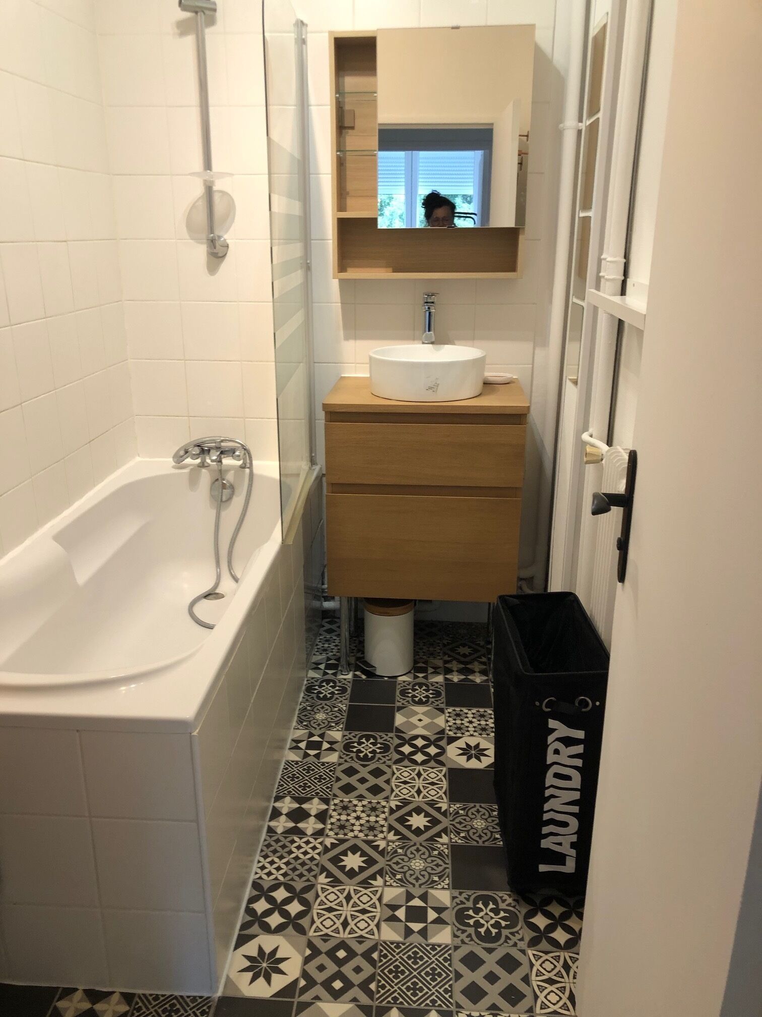 Een badkamer met een bad, een wastafel, een spiegel en een vloer met een patroon.